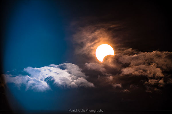 A partial solar eclipse photographed through clouds.