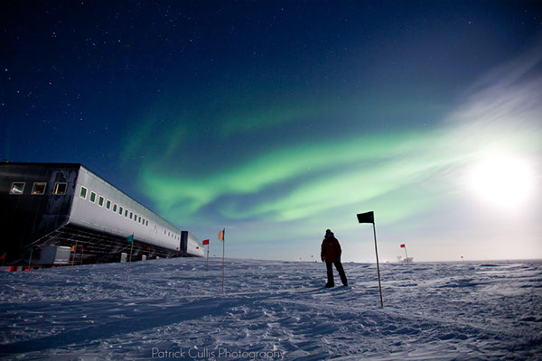 Self portrait in front of the Amundsen-Scott South Pole Station in Antarctica by moonlight with aurora.